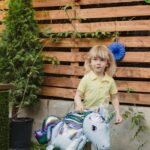A young child enjoying an outdoor birthday party with colorful decor and a unicorn balloon.
