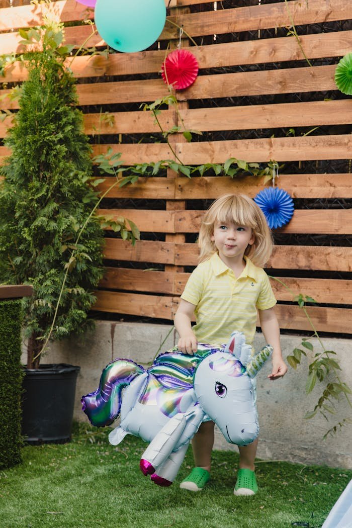 A young child enjoying an outdoor birthday party with colorful decor and a unicorn balloon.
